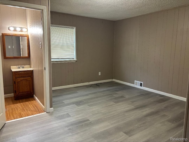 6303 Duncan St, Taylor, MI 48180 - unfurnished bedroom featuring wood finished floors, wood walls, a textured ceiling, and connected bathroom