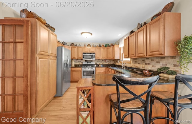115 Audubon Dr, White Lake, MI 48383 - kitchen featuring stainless steel appliances, light wood-style flooring, a peninsula, a breakfast bar area, and tasteful backsplash