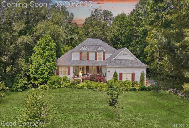 115 Audubon Dr, White Lake, MI 48383 - traditional-style house with covered porch, a front yard, and a shingled roof