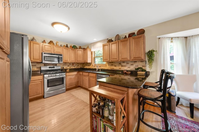 115 Audubon Dr, White Lake, MI 48383 - kitchen with stainless steel appliances, a kitchen breakfast bar, decorative backsplash, and a peninsula