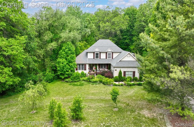 115 Audubon Dr, White Lake, MI 48383 - traditional home with covered porch, a front lawn, and a forest view