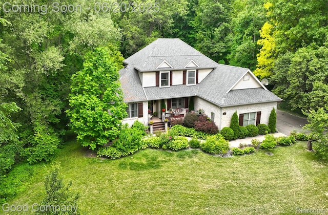 115 Audubon Dr, White Lake, MI 48383 - view of front of property with covered porch, a front lawn, and a wooded view