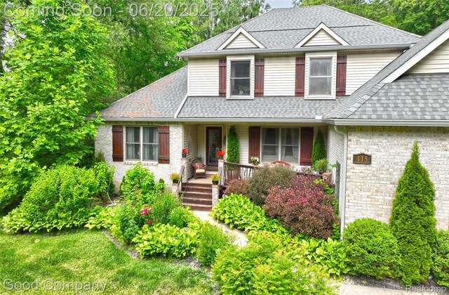 115 Audubon Dr, White Lake, MI 48383 - view of front of house with covered porch, a shingled roof, and brick siding