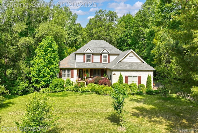 115 Audubon Dr, White Lake, MI 48383 - traditional-style house with covered porch, a front lawn, and roof with shingles