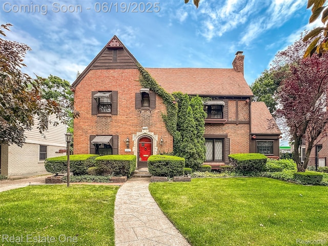 26044 York Rd, Huntington Woods, MI 48070 - tudor-style house with brick siding, a front yard, and a chimney
