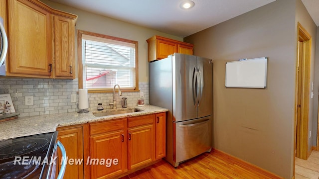 3137 Sundown Ln, Saginaw, MI 48603 - kitchen featuring freestanding refrigerator, backsplash, light stone countertops, and light wood-style floors
