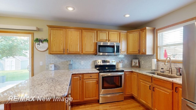 3137 Sundown Ln, Saginaw, MI 48603 - kitchen featuring stainless steel appliances, a peninsula, decorative backsplash, light stone counters, and recessed lighting