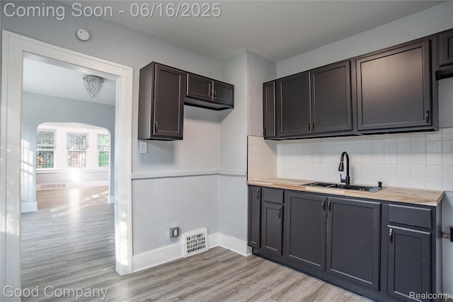 5217 Lakeview St, Detroit, MI 48213 - kitchen with butcher block counters, light wood-style flooring, backsplash, and arched walkways