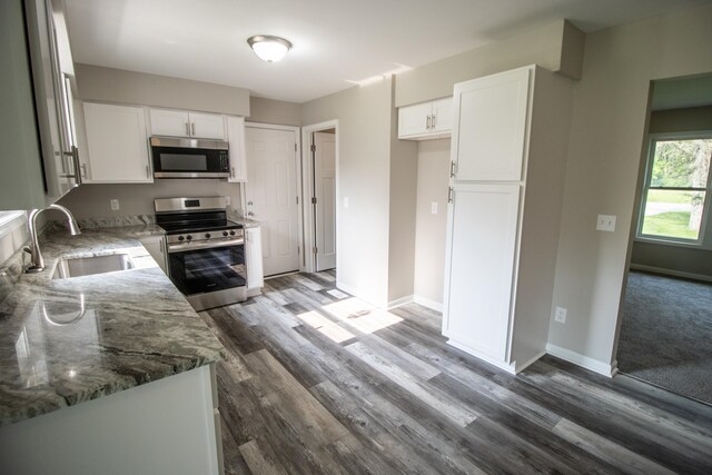 9461 Morrish Rd, Montrose, MI 48457 - kitchen with stainless steel appliances, white cabinetry, light stone counters, and wood finished floors