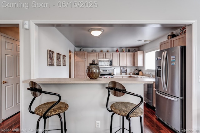 28498 Carlton Way Dr, Novi, MI 48377 - kitchen with stainless steel appliances, dark wood finished floors, a kitchen breakfast bar, and light countertops