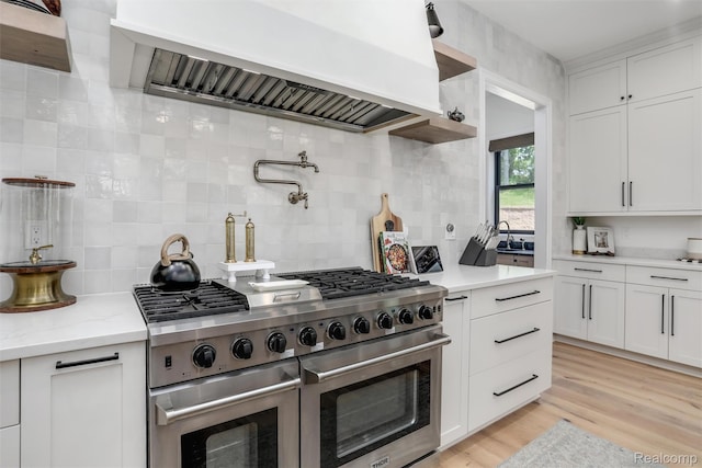 2584 Heights View Ct, Rochester, MI 48306 - kitchen with double oven range, custom exhaust hood, backsplash, white cabinets, and light wood finished floors