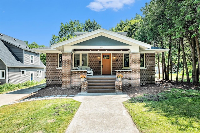 1412 4th St NW, Grand Rapids, MI 49504 - bungalow-style home with brick siding, covered porch, and a front lawn