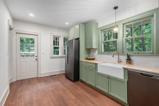 1412 4th St NW, Grand Rapids, MI 49504 - kitchen with green cabinets, stainless steel appliances, dark wood finished floors, backsplash, and pendant lighting