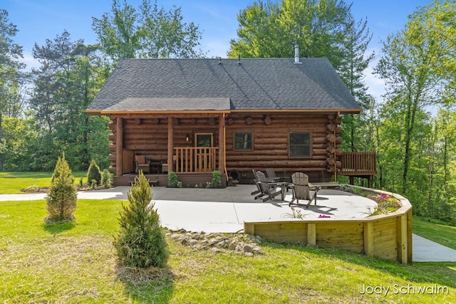 5820 Grace Hwy, Sunfield, MI 48890 - back of property featuring log siding, a yard, a patio area, and a shingled roof