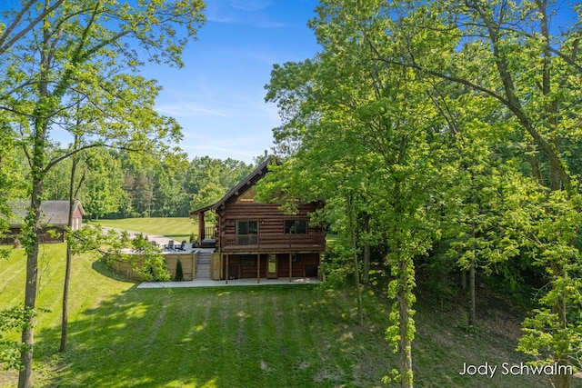 5820 Grace Hwy, Sunfield, MI 48890 - rear view of house featuring log siding, a yard, a patio, a wooden deck, and a forest view