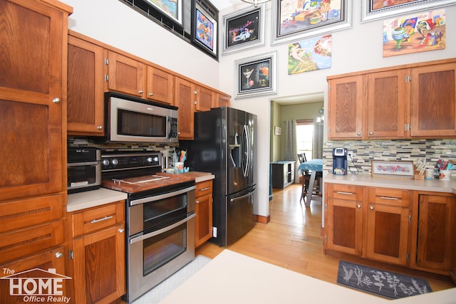 2411 Escott Rd, Owosso, MI 48867 - kitchen featuring appliances with stainless steel finishes, light countertops, decorative backsplash, light wood-style flooring, and brown cabinets