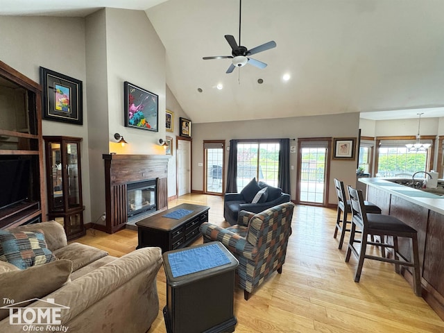 2411 Escott Rd, Owosso, MI 48867 - living area featuring a glass covered fireplace, light wood-style flooring, ceiling fan, plenty of natural light, and high vaulted ceiling
