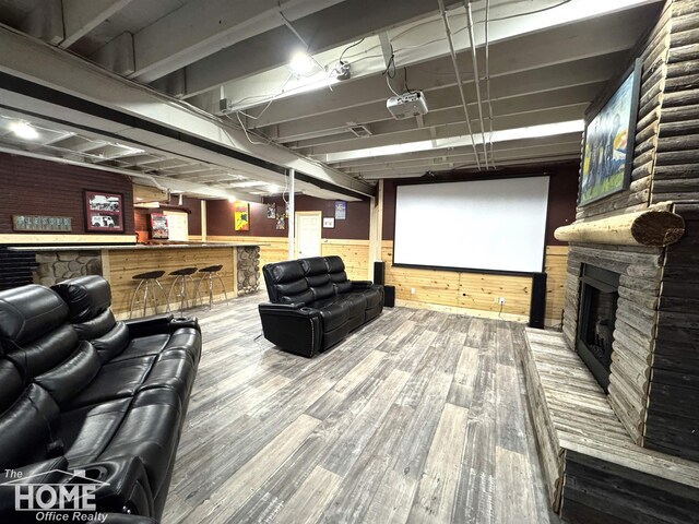 2411 Escott Rd, Owosso, MI 48867 - home theater room with wood finished floors, wood walls, a stone fireplace, and bar area