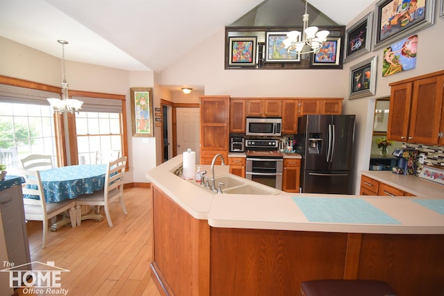 2411 Escott Rd, Owosso, MI 48867 - kitchen with a chandelier, stainless steel appliances, brown cabinets, light countertops, and high vaulted ceiling