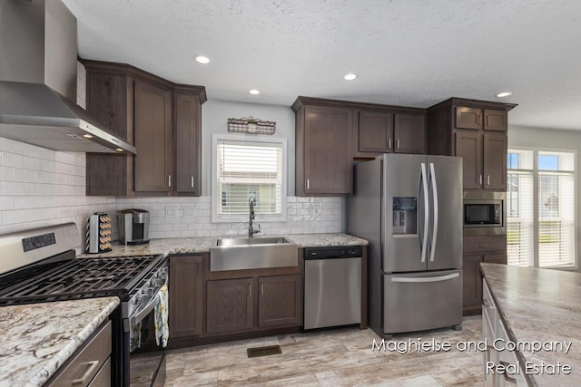 5231 E Scenic Turn Ln, Holland, MI 49423 - kitchen with appliances with stainless steel finishes, wall chimney exhaust hood, plenty of natural light, dark brown cabinets, and recessed lighting