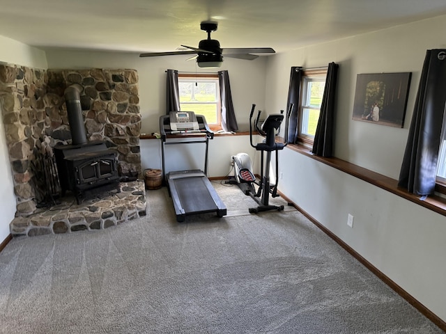 11199 Edgewood Rd, Bellevue, MI 49021 - exercise room featuring carpet, a ceiling fan, plenty of natural light, and a wood stove