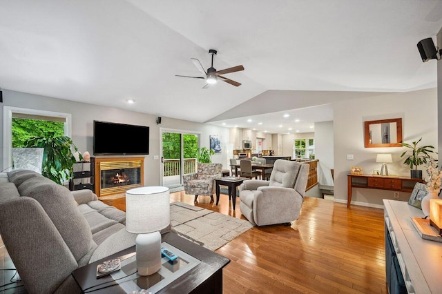 3999 Ravina Ter, Saint Joseph, MI 49085 - living room featuring vaulted ceiling, plenty of natural light, a ceiling fan, light wood finished floors, and a glass covered fireplace