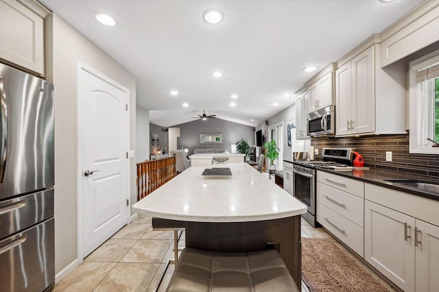 3999 Ravina Ter, Saint Joseph, MI 49085 - kitchen with stainless steel appliances, lofted ceiling, open floor plan, decorative backsplash, and a kitchen island