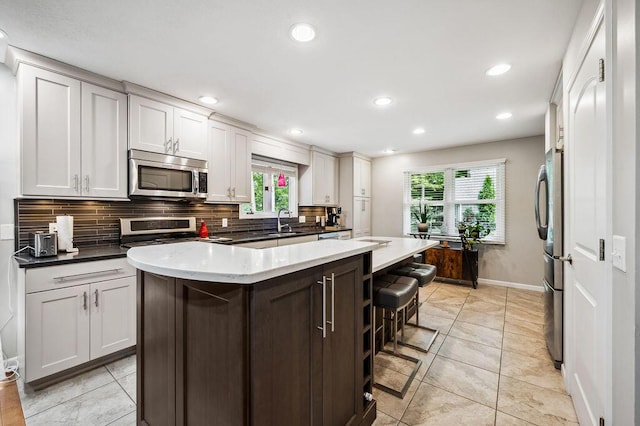 3999 Ravina Ter, Saint Joseph, MI 49085 - kitchen featuring appliances with stainless steel finishes, decorative backsplash, healthy amount of natural light, a breakfast bar, and recessed lighting