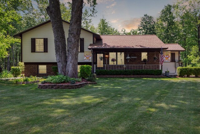 10343 N Walnut Ave, Bitely, MI 49309 - tri-level home with brick siding, a front lawn, and a porch