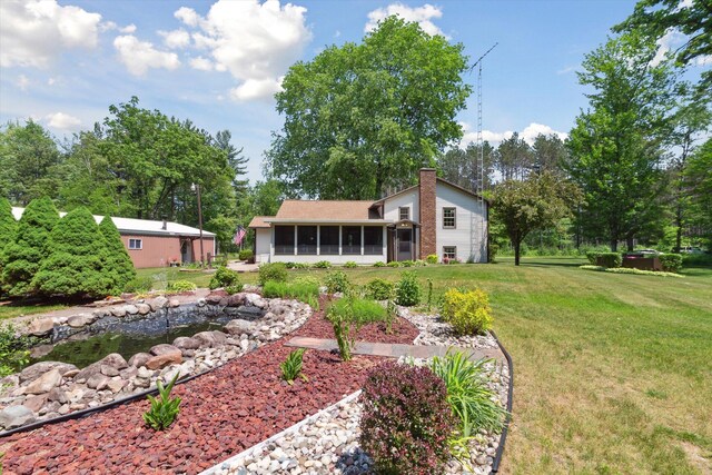 10343 N Walnut Ave, Bitely, MI 49309 - rear view of property featuring a sunroom, a chimney, a yard, and a small pond