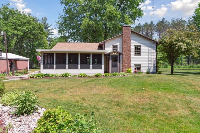 10343 N Walnut Ave, Bitely, MI 49309 - back of house featuring a sunroom, a chimney, a lawn, and roof with shingles