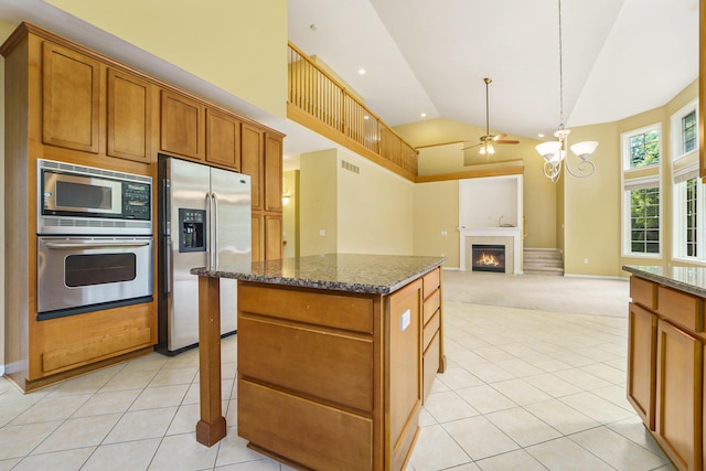 2032 Cameo Ct, Canton, MI 48187 - kitchen featuring appliances with stainless steel finishes, high vaulted ceiling, a warm lit fireplace, dark stone counters, and brown cabinets