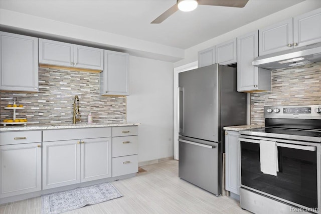 20401 Anglin St, Detroit, MI 48234 - kitchen featuring appliances with stainless steel finishes, under cabinet range hood, ceiling fan, decorative backsplash, and light stone countertops