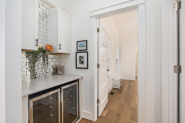 7285 Maple St, South Haven, MI 49090 - indoor dry bar featuring wine cooler, backsplash, and light wood-style floors