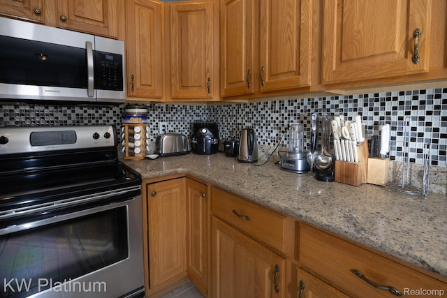 3167 Blackheath Ct, Port Huron, MI 48060 - kitchen with appliances with stainless steel finishes, backsplash, brown cabinets, and light stone countertops
