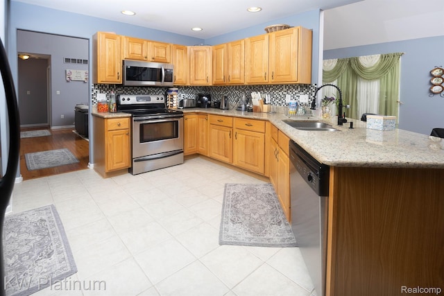 3167 Blackheath Ct, Port Huron, MI 48060 - kitchen with appliances with stainless steel finishes, decorative backsplash, light stone countertops, a peninsula, and recessed lighting