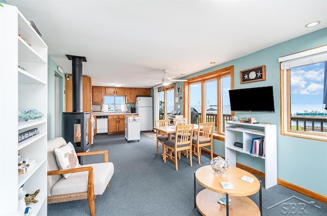 6276 W Houghton Lake Dr, Houghton Lake, MI 48629 - dining area featuring a wood stove, dark colored carpet, a ceiling fan, and recessed lighting