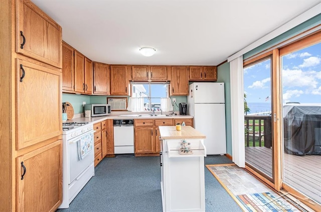 6276 W Houghton Lake Dr, Houghton Lake, MI 48629 - kitchen featuring white appliances, light countertops, dark colored carpet, a kitchen island, and brown cabinets