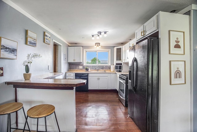 3463 Arthur Rd, Remus, MI 49340 - kitchen with black appliances, a peninsula, a breakfast bar, white cabinetry, and dark wood-style floors