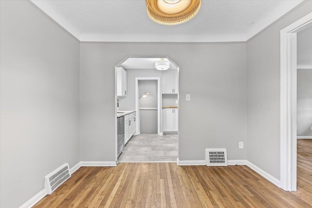 22406 Colony St, Saint Clair Shores, MI 48080 - unfurnished dining area with light wood-style flooring, arched walkways, a textured ceiling, and crown molding