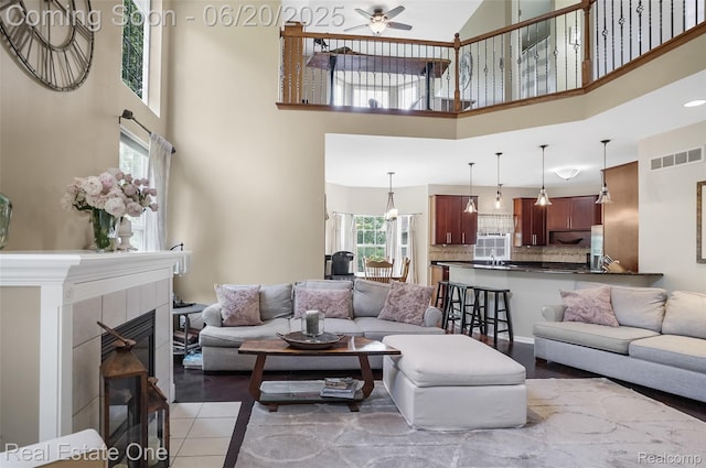 9806 Goldfinch Ct, Saline, MI 48176 - living area featuring a high ceiling, a ceiling fan, healthy amount of natural light, a tile fireplace, and light tile patterned floors
