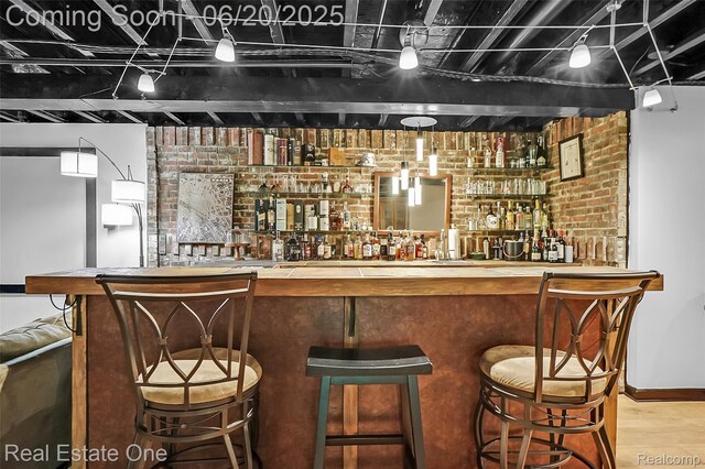 9806 Goldfinch Ct, Saline, MI 48176 - indoor wet bar with brick wall and wood finished floors