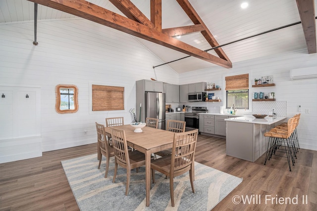 10296 S Lakeside Ridge Rd, Baldwin, MI 49304 - dining space featuring beam ceiling, an AC wall unit, wood finished floors, and high vaulted ceiling
