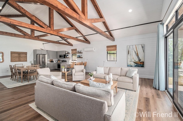 10296 S Lakeside Ridge Rd, Baldwin, MI 49304 - living area with an AC wall unit, plenty of natural light, light wood finished floors, beam ceiling, and high vaulted ceiling
