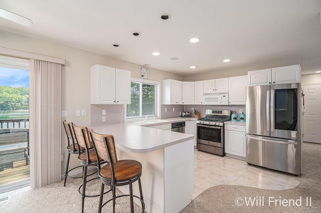 10296 S Lakeside Ridge Rd, Baldwin, MI 49304 - kitchen with appliances with stainless steel finishes, a peninsula, recessed lighting, white cabinetry, and a kitchen bar