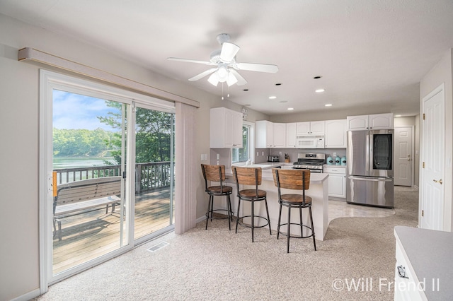 10296 S Lakeside Ridge Rd, Baldwin, MI 49304 - kitchen featuring appliances with stainless steel finishes, white cabinets, a peninsula, ceiling fan, and a breakfast bar area