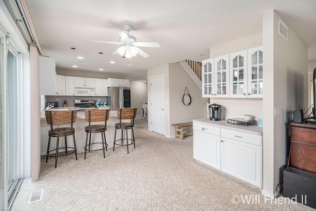 10296 S Lakeside Ridge Rd, Baldwin, MI 49304 - kitchen with appliances with stainless steel finishes, a breakfast bar, glass insert cabinets, a peninsula, and a ceiling fan