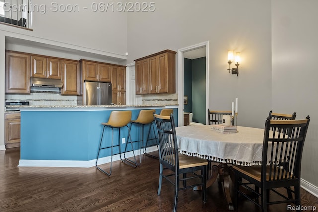 4376 Bennett Park Cir, Troy, MI 48085 - kitchen featuring freestanding refrigerator, under cabinet range hood, dark wood-style flooring, decorative backsplash, and a high ceiling