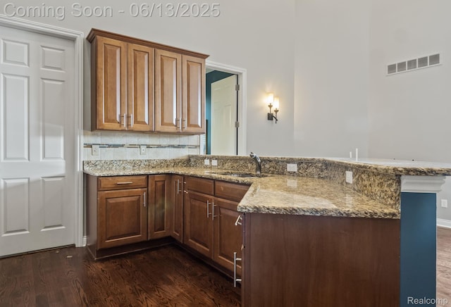 4376 Bennett Park Cir, Troy, MI 48085 - kitchen featuring dark wood-style flooring, light stone counters, a peninsula, and backsplash