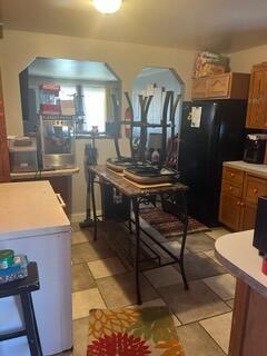 2928 Austin St, Muskegon, MI 49444 - kitchen with arched walkways, brown cabinets, freestanding refrigerator, and light countertops